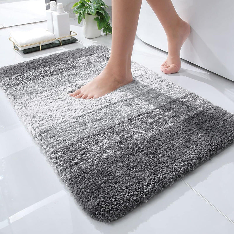 Gray gradient microfiber bath mat with non-slip backing, on a bathroom floor beside a tub