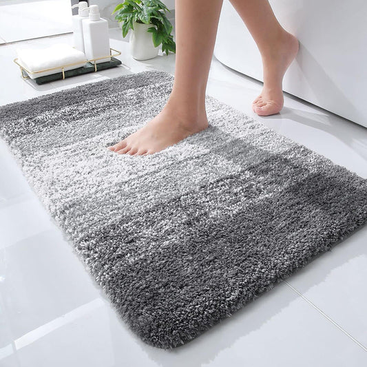 Gray gradient microfiber bath mat with non-slip backing, on a bathroom floor beside a tub